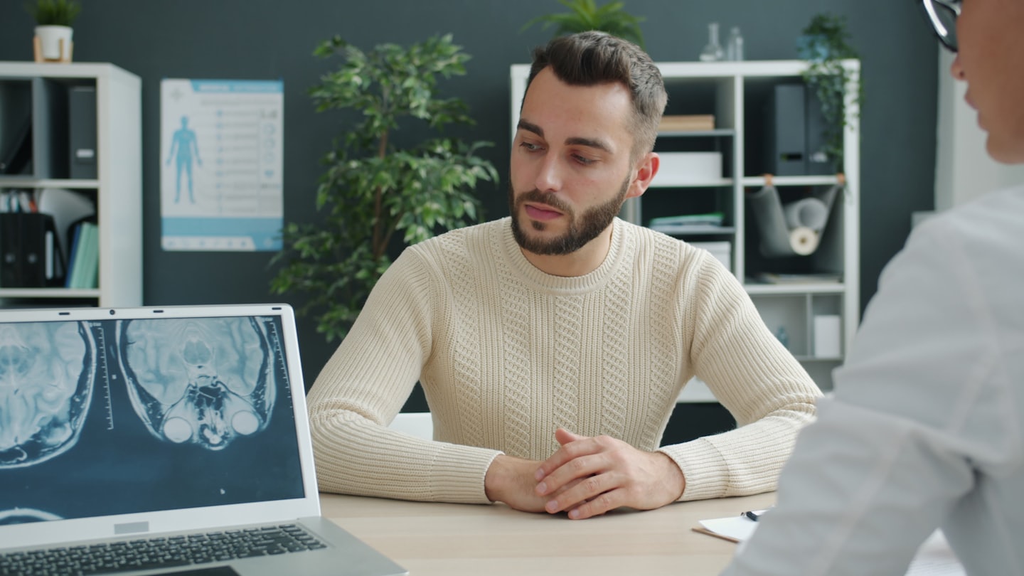 Lekarz omawia wyniki skanu mózgu z pacjentem przez laptopa.